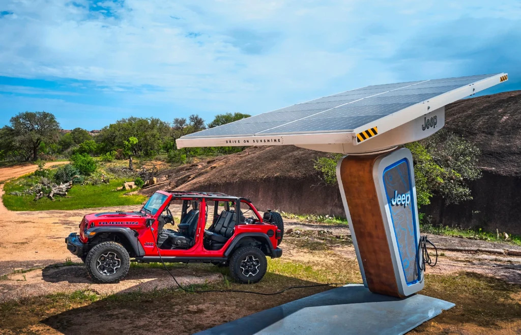 Jeep Wrangler da Stellantis sendo abastecido por energia elétrica em uma estação de recarga em zona rural.