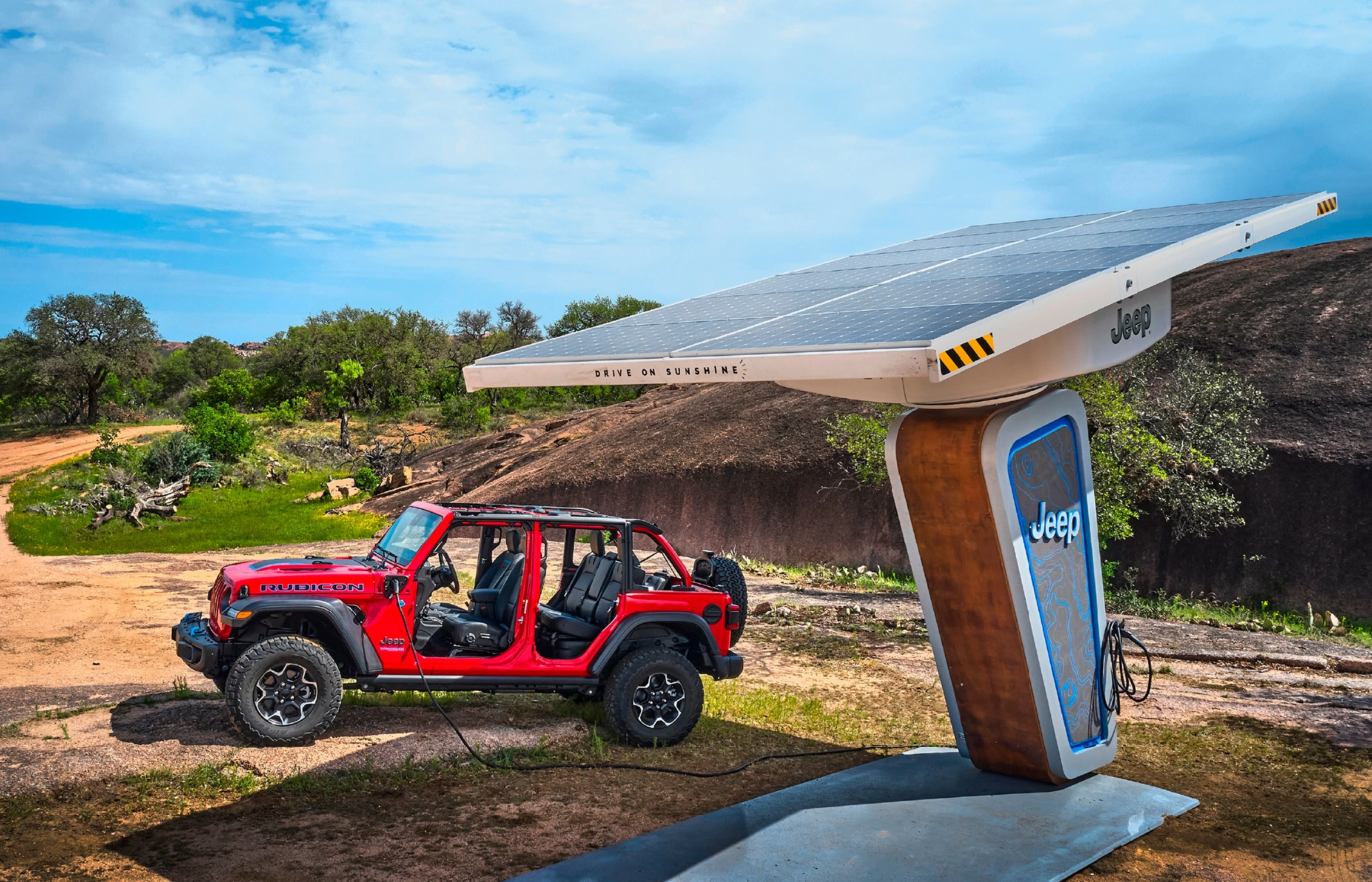 Jeep Wrangler da Stellantis sendo abastecido por energia elétrica em uma estação de recarga em zona rural.